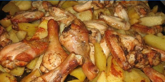 Chicken legs with potatoes on a baking sheet