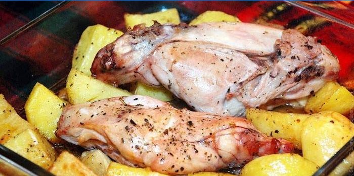 Rabbit meat on a pillow of potatoes before baking