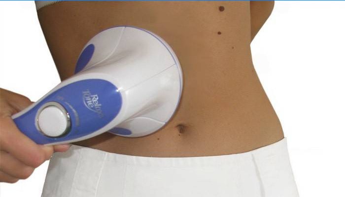 Woman makes self-massage of the abdomen with a massager