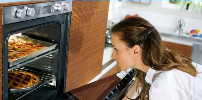 Girl looks at pastries in the oven