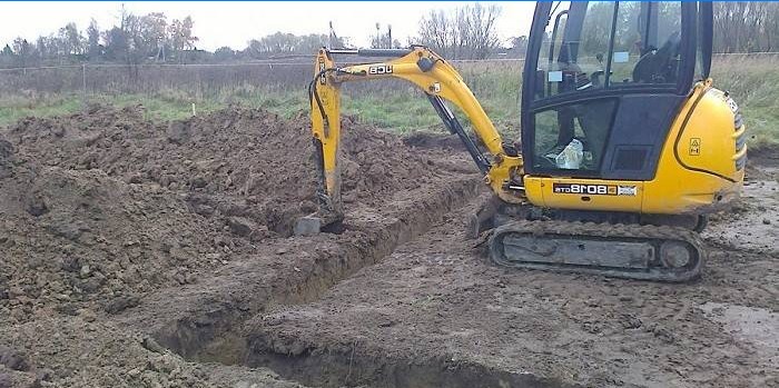 Excavator digs trenches on the site