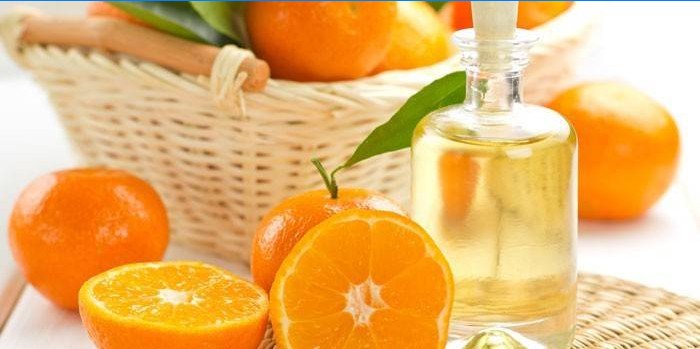 Orange oil in a jar and oranges