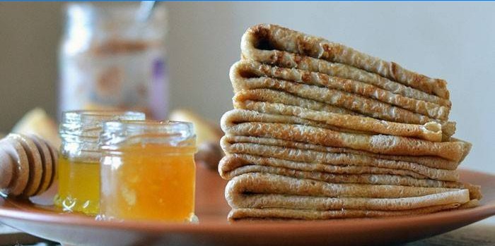 A stack of pancakes and a jar of honey