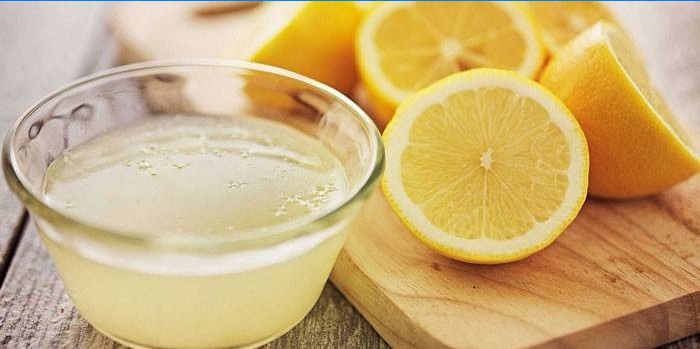 Lemon juice in a bowl and half lemons