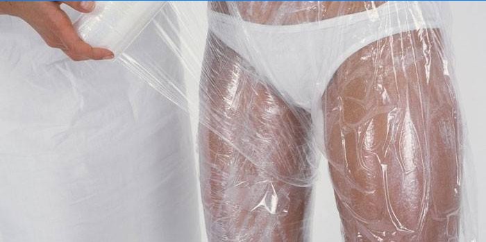 Girl doing wrap of legs and abdomen with cling film