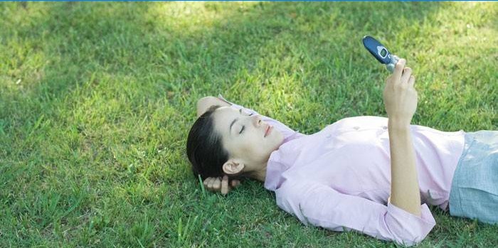 The girl lies on the grass with a phone