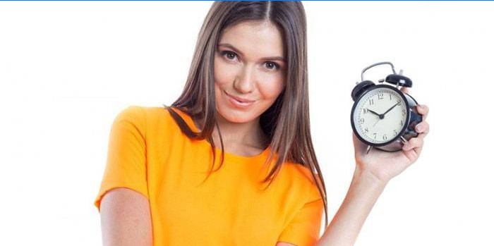 Girl holds an alarm clock in a hand