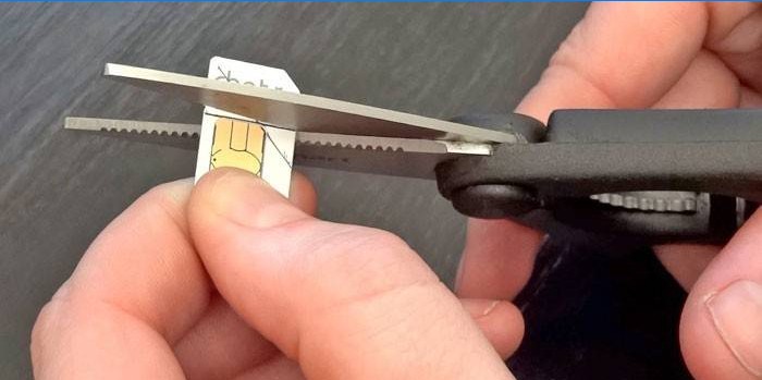 A man cuts a sim card according to the pattern with scissors