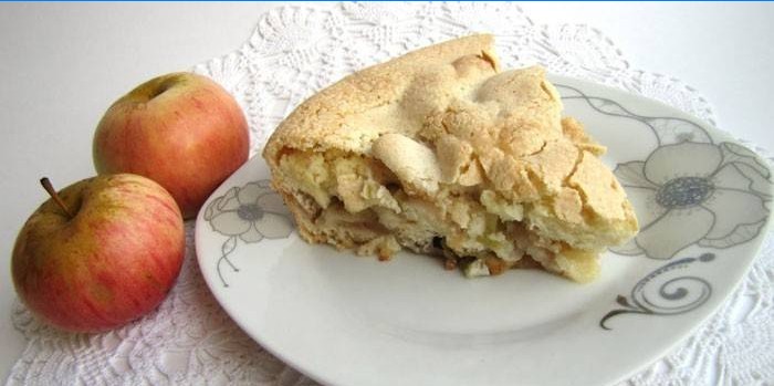 A slice of apple pie on a plate and apples