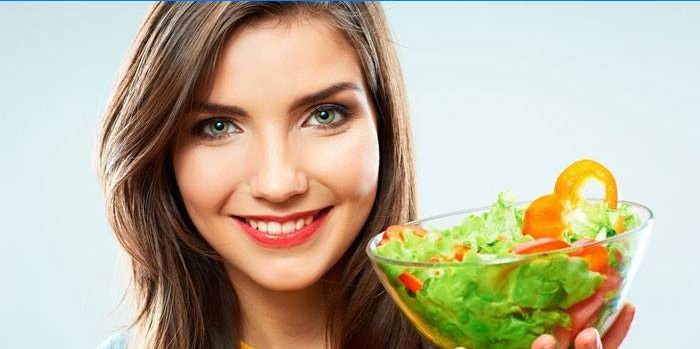Girl holds a plate with salad