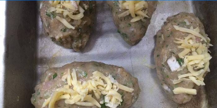 Pork patties with cheese on a baking sheet