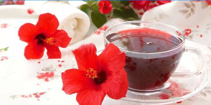 Hibiscus tea in a cup and hibiscus flowers