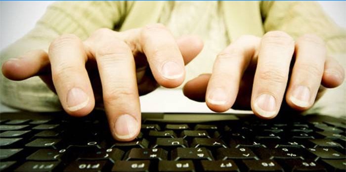 Fingers of a man above a computer keyboard