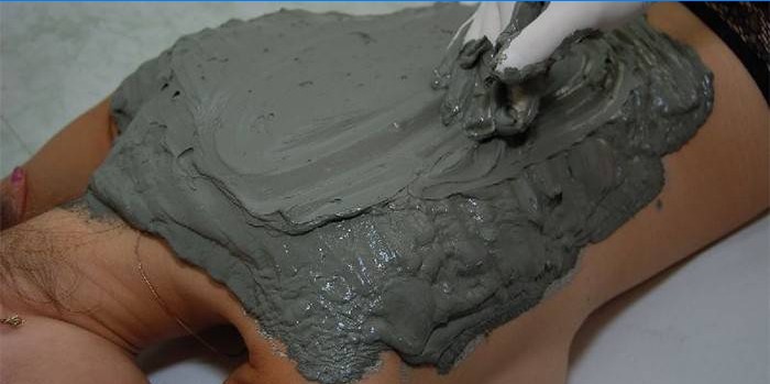 Putting blue clay on the back of a girl