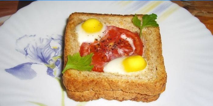 Hot sandwich with quail eggs and tomato on a plate