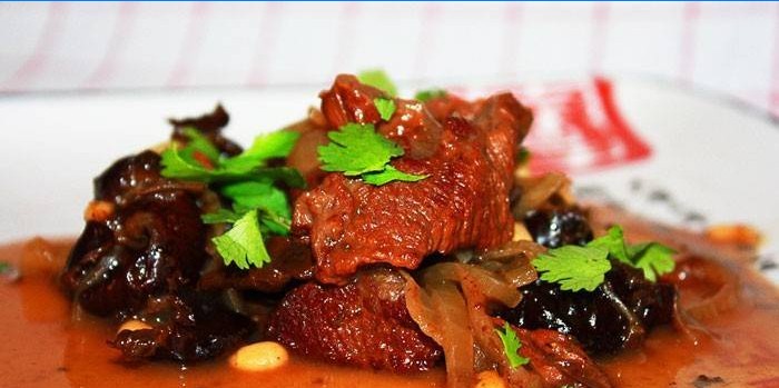 Braised beef with prunes and sauce on a plate