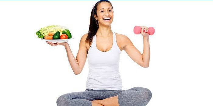 Girl with a plate of vegetables and a dumbbell in hands