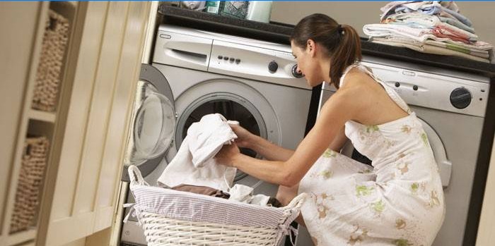 Girl puts towels in a washing machine