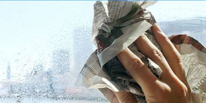 Man rubs window glass with newspaper