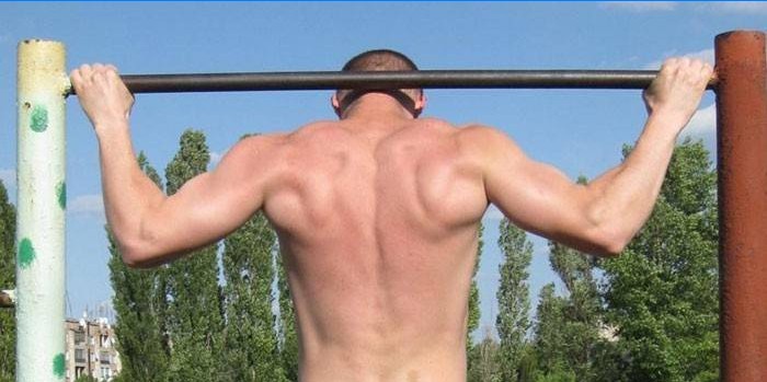 A man performs a pull-up with a bar behind his head