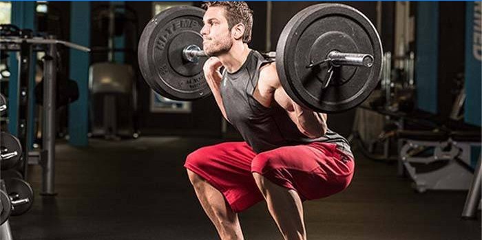Guy crouches with barbell