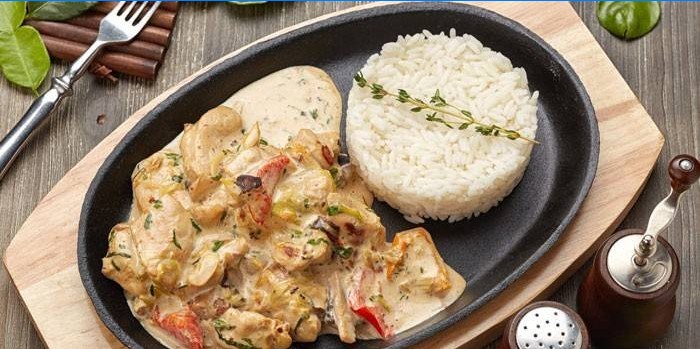 Sliced ​​chicken in a creamy sauce with rice garnished
