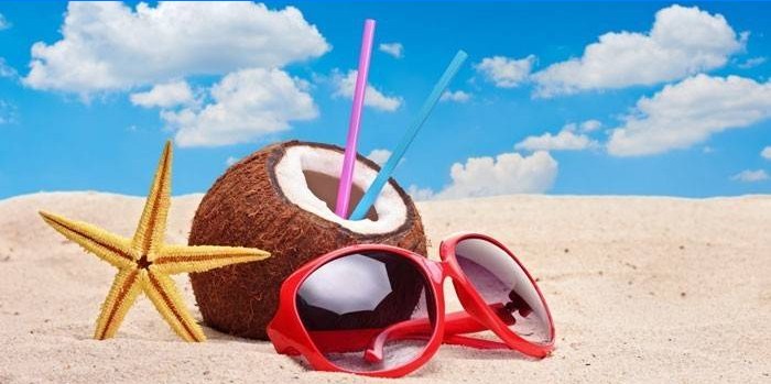 Coconut and glasses on the sand