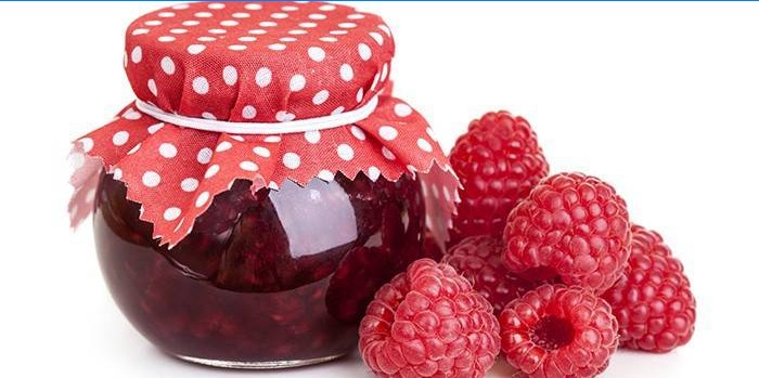 Jar with raspberry jam and raspberries