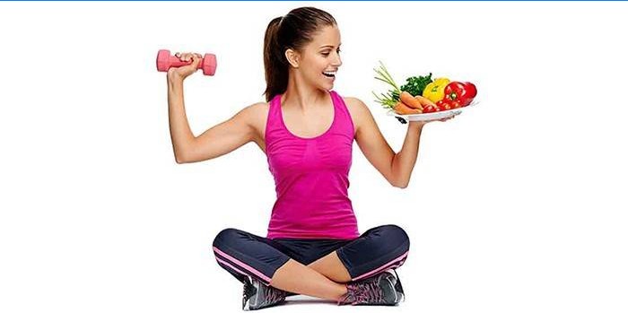 Girl holds dumbbells and a plate with vegetables in her hands