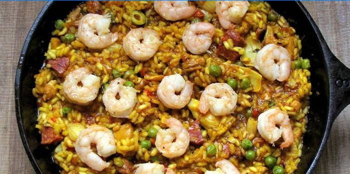 Paella with meat and prawns in a pan