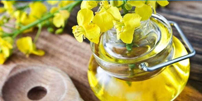 Rapeseed oil in a jar and rapeseed flowers