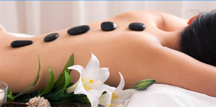 Girl at the spa procedure with warm stones