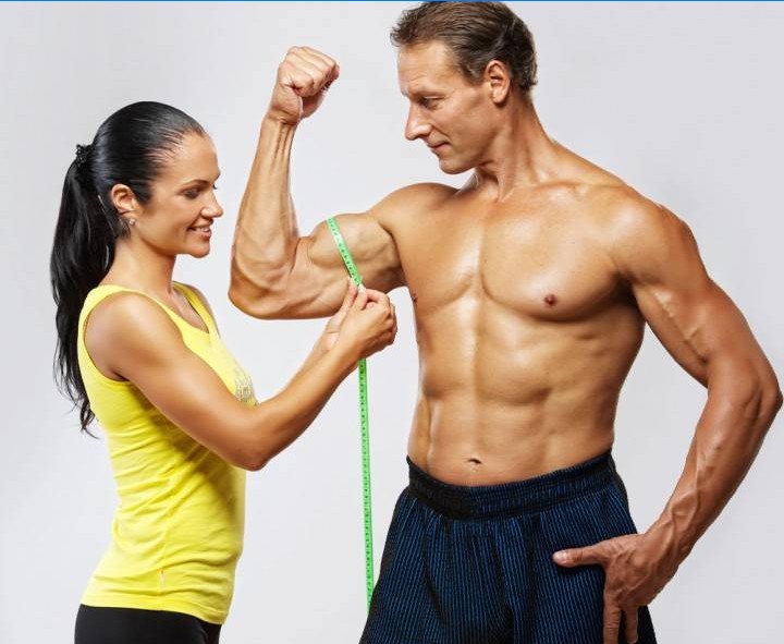 The girl measures the amount of muscle in the arm of a man