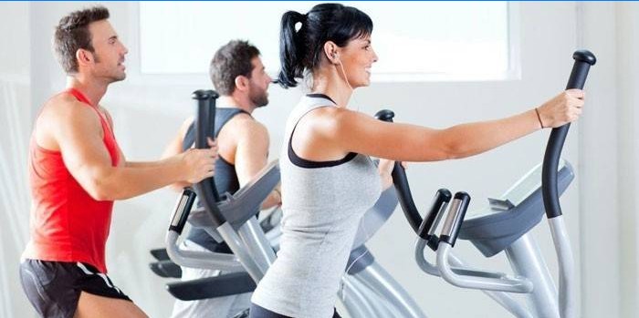 Men and women work out on elliptical trainers.