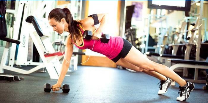 Girl doing exercise with dumbbells in the gym.