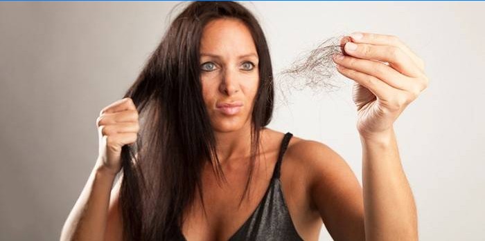 Woman holds a tuft of hair in her hand