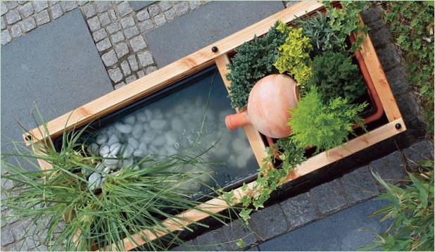 Arrangement of a mini pond with a flowerpot on a plot